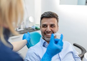 a dental assistant handing a man Invisalign trays