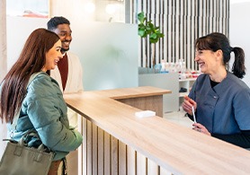 a couple checking out at the front desk of a dental office