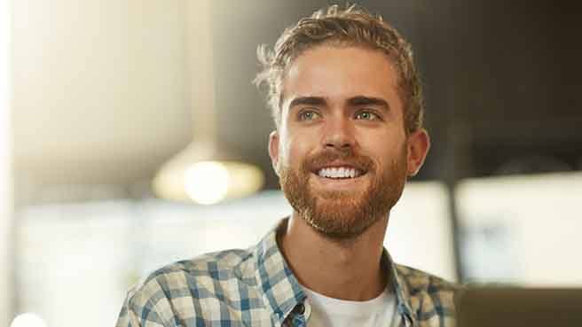 a man smiling and using his laptop