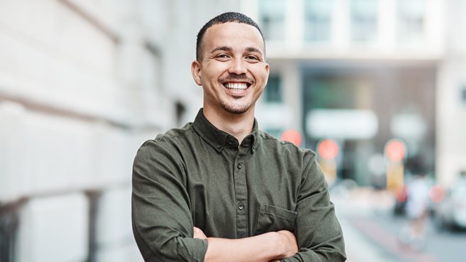 a man smiling with his arms crossed