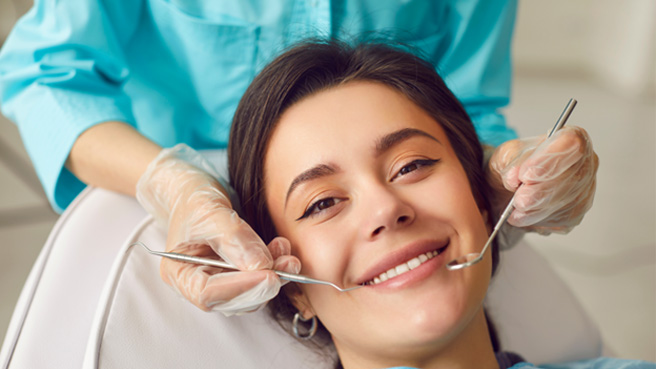 a smiling woman having her teeth examined
