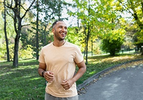 a smiling man going for a jog outdoors