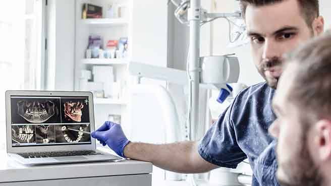 a dentist showing a patient his X-rays and oral scans