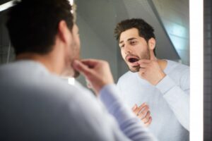 a man looking at his teeth in a mirror